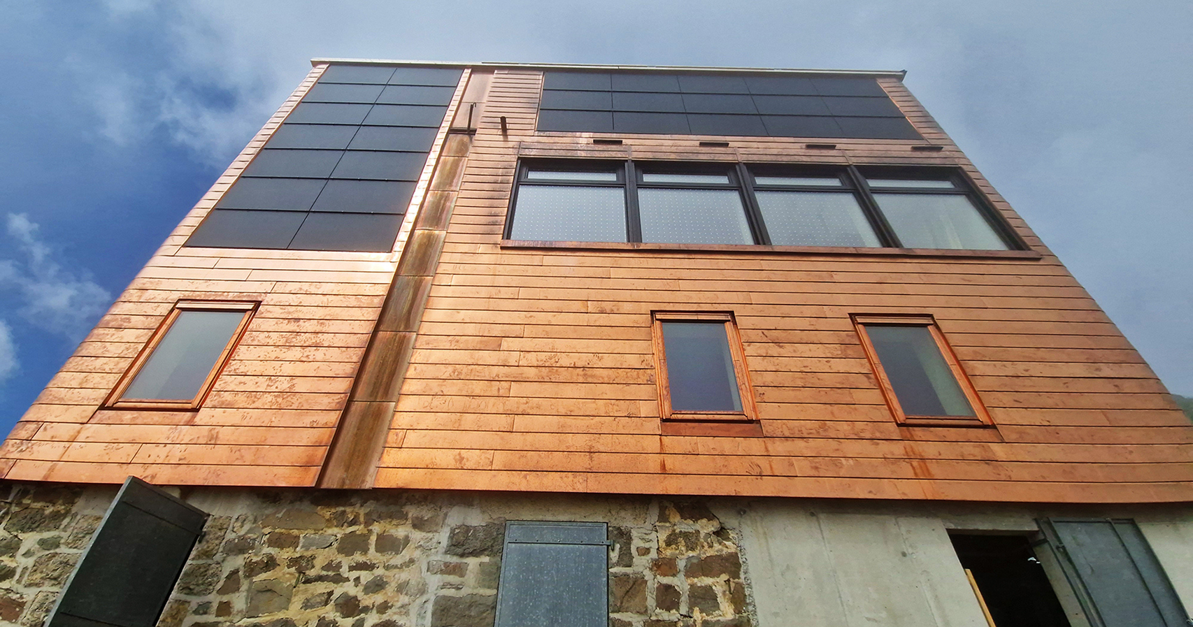 Photo d’une des façades du bâtiment après les travaux avec les panneaux photovoltaïques déjà posés.