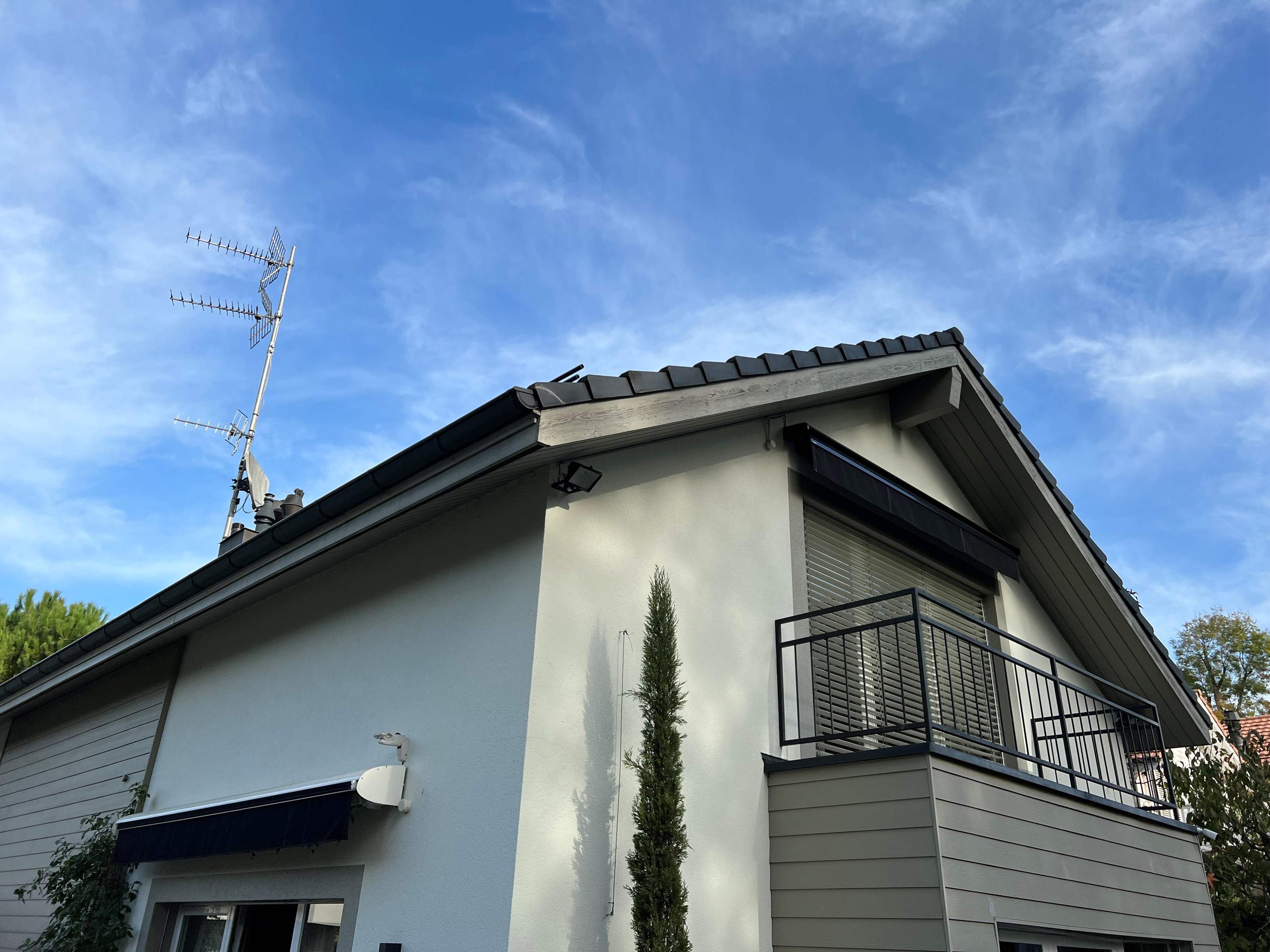 Maison familiale à toit en pente à Anières avec antennes TV, avant l'installation de panneaux solaires.