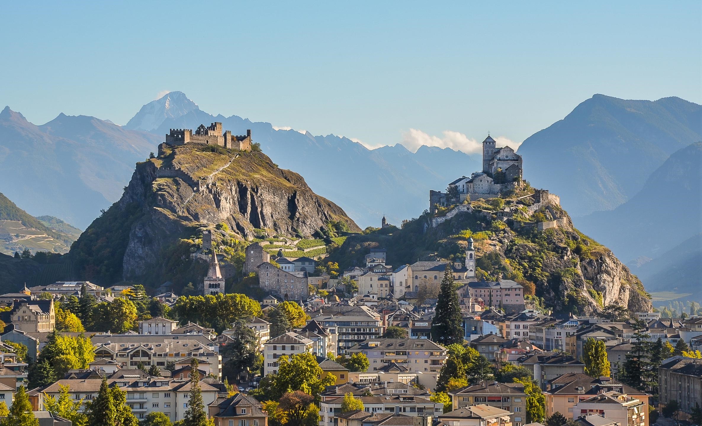 Vue panoramique de la ville de Sion avec les châteaux de Tourbillon et Valère perchés sur leurs collines, au cœur du Valais en Suisse.