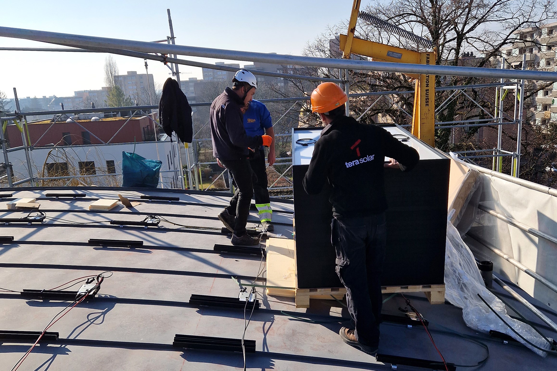 Livraison de panneaux solaires sur le toit à l’aide d’un palan, techniciens de Tera Solar en pleine préparation de l'installation.