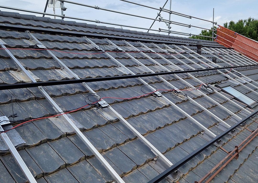 Panneaux photovoltaïques sur toiture plate avec système de lestage, modules noirs en rangées avec filet orange.