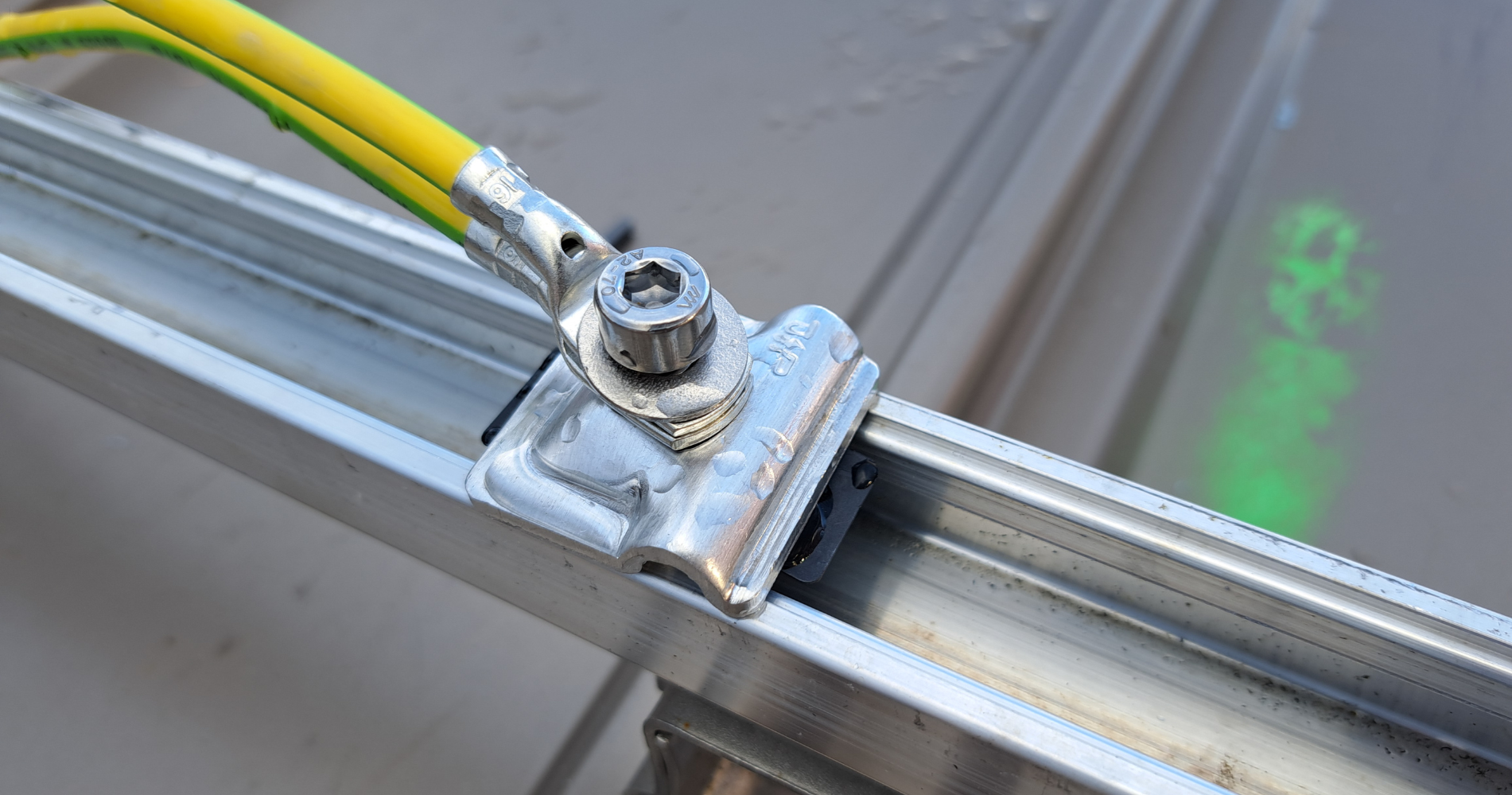 Fixation de câble de mise à la terre sur une structure métallique d’installation photovoltaïque, assurant la sécurité électrique du système solaire.