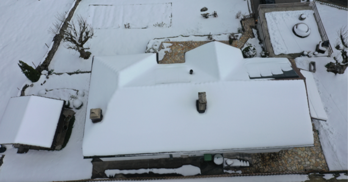Vue aérienne de la maison avec la toiture entièrement enneigée, avant l’installation photovoltaïque.