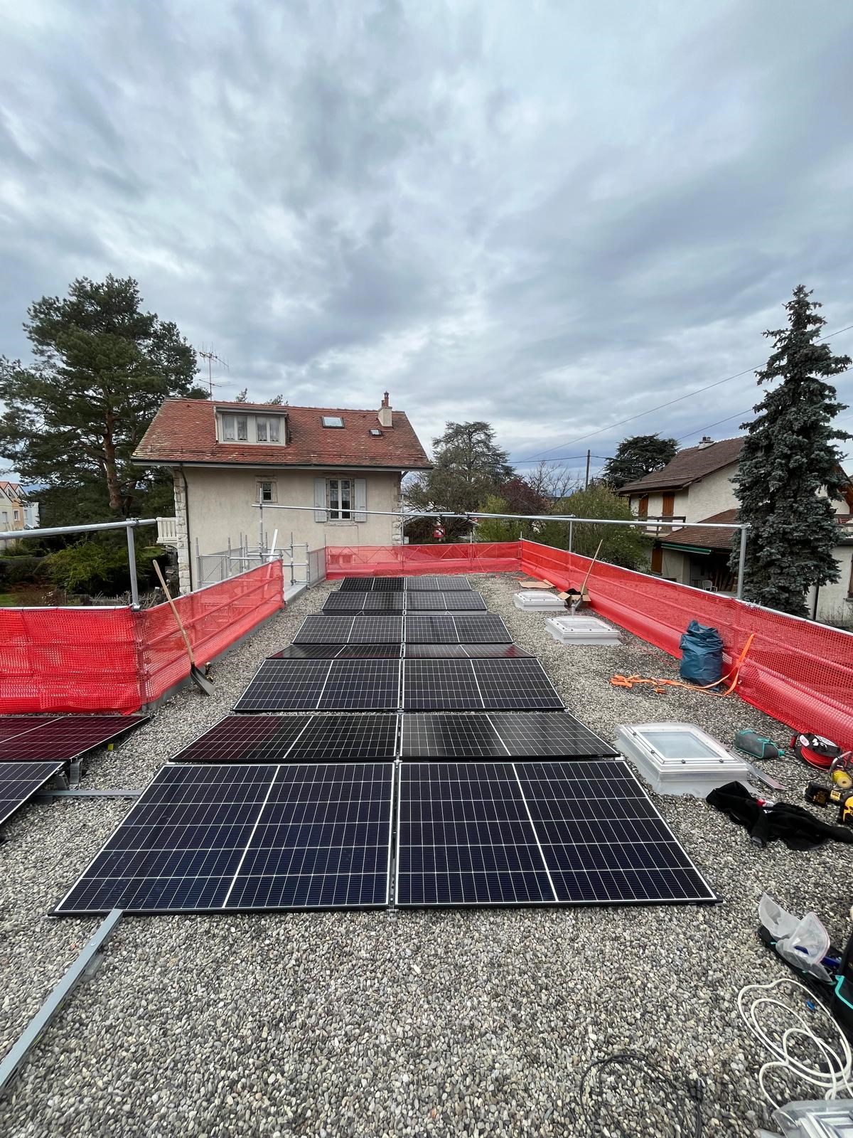 Pose de panneaux photovoltaïques sur toiture plate d’une maison en Suisse, dans le cadre d’une installation solaire résidentielle en zone urbaine.