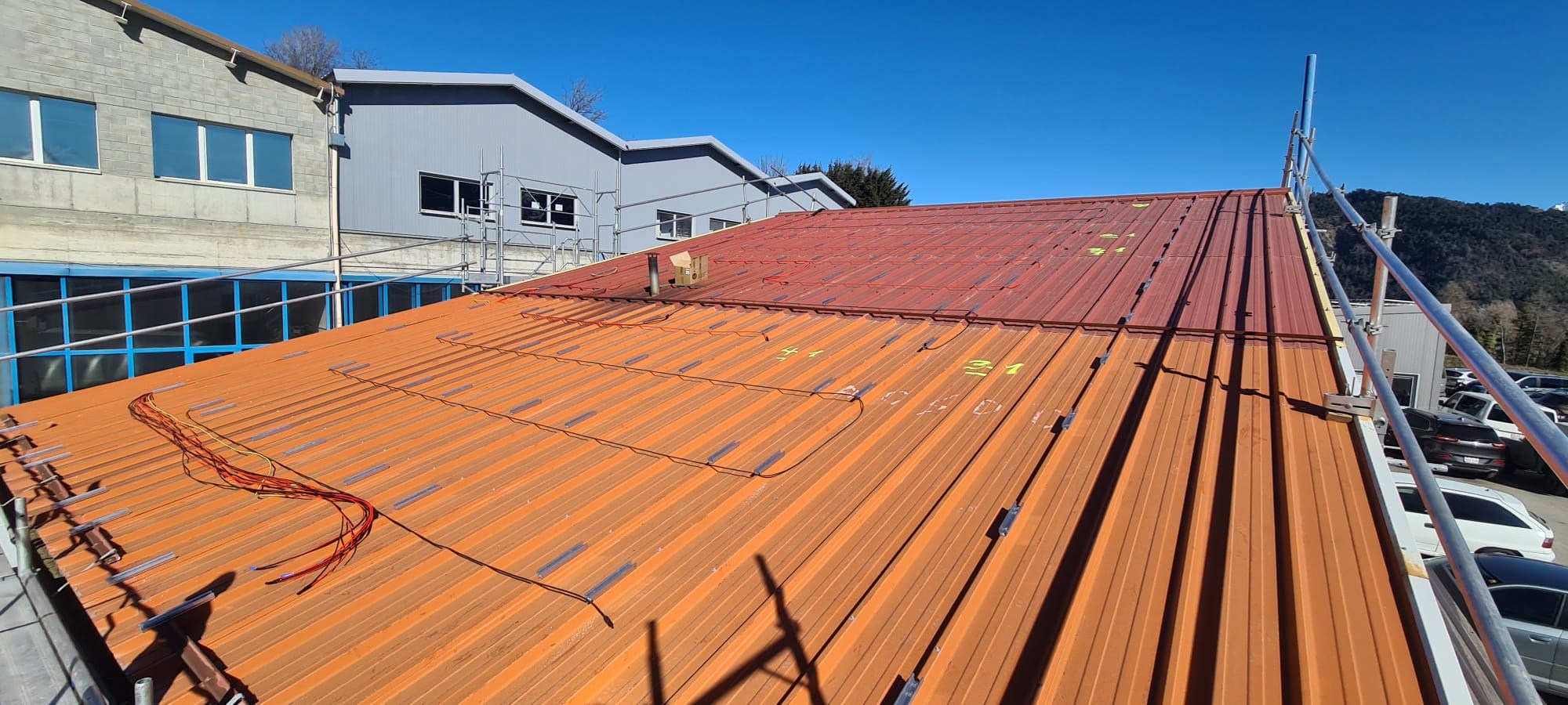 Panneaux photovoltaïques sur toiture plate avec système de lestage, modules noirs en rangées avec filet orange.