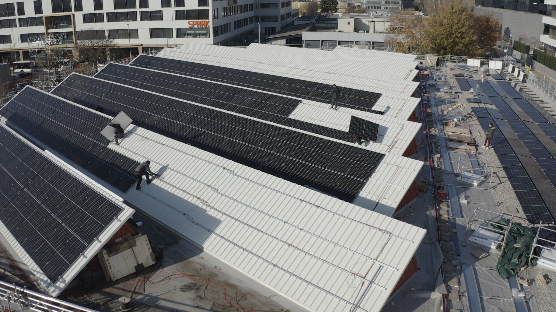 Installation en cours de panneaux solaires sur un toit en sheds d’un bâtiment industriel en rénovation, pour une production locale d’électricité verte.
