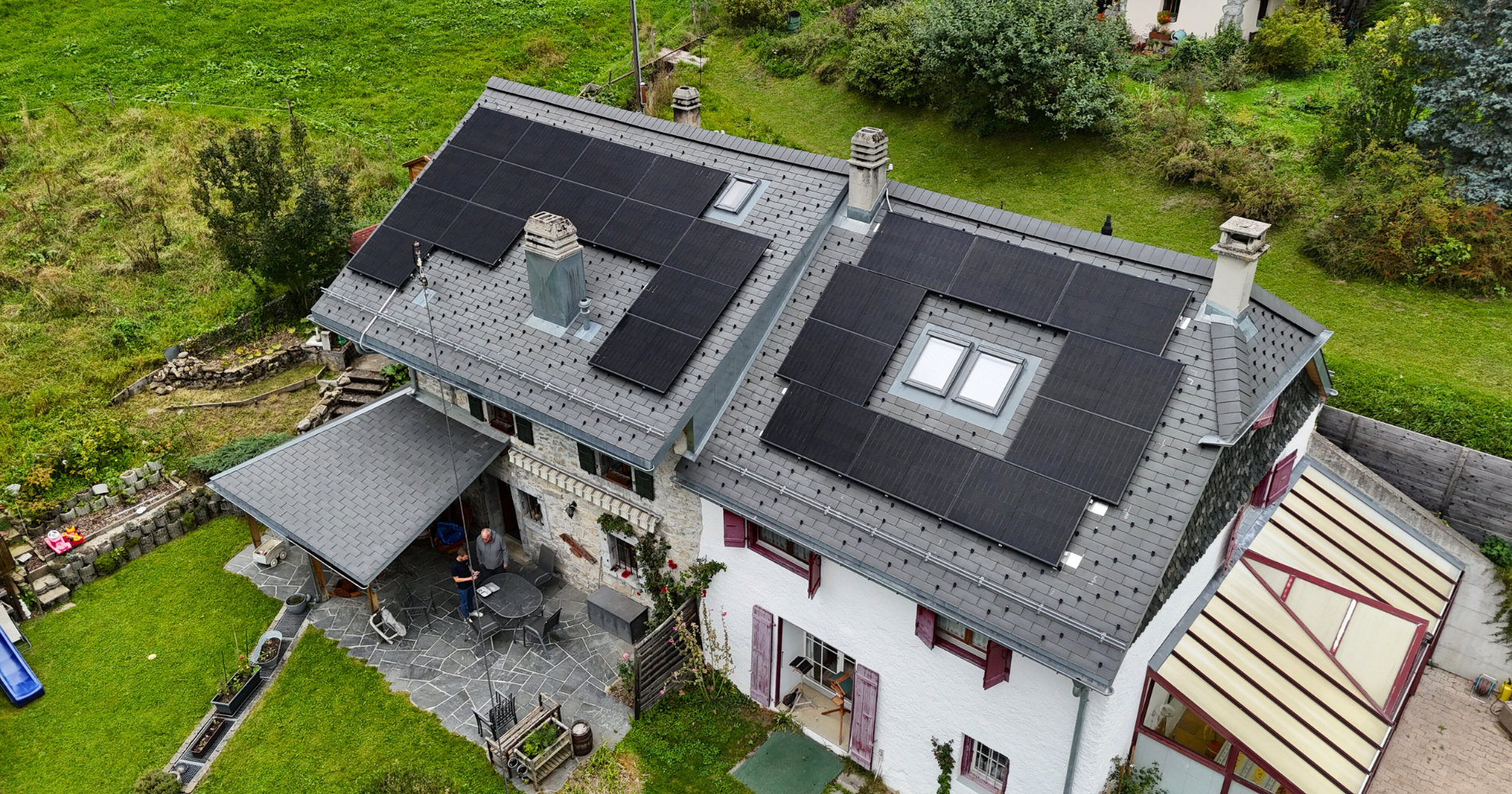 vue aérienne montrant des panneaux solaires full black intégrés sur une toiture inclinée dans un quartier résidentiel.