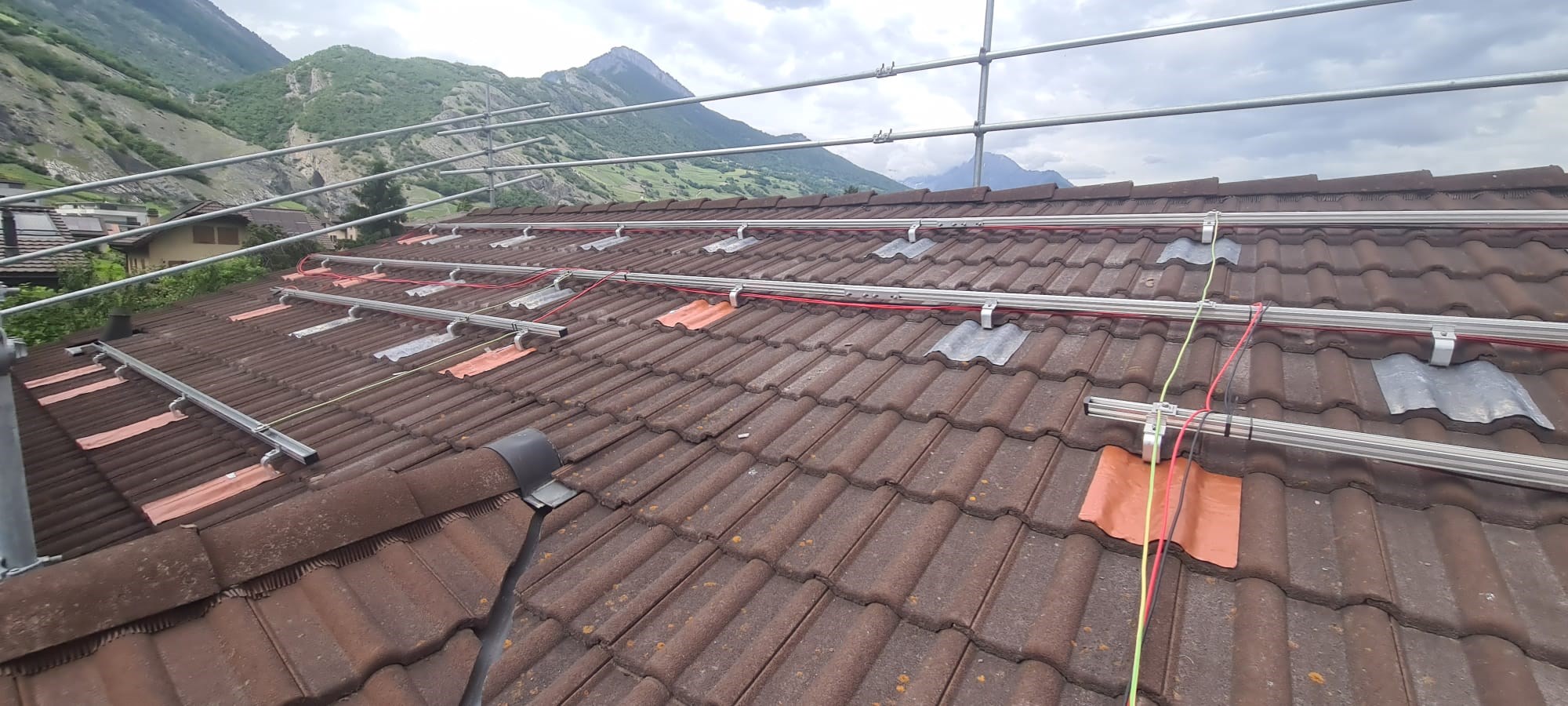 Panneaux photovoltaïques sur toiture plate avec système de lestage, modules noirs en rangées avec filet orange.