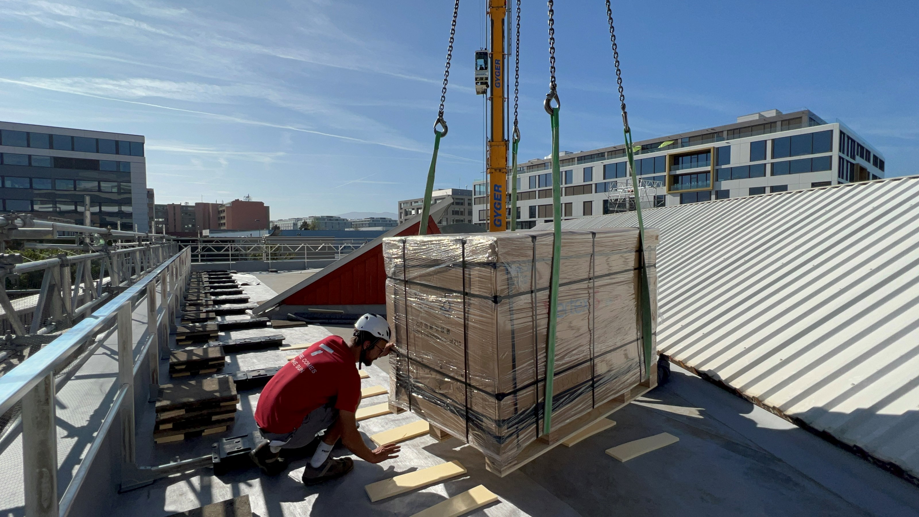 Livraison sécurisée de matériel photovoltaïque sur toiture, préparation de l’installation solaire en site urbain avec grue et manutention manuelle.
