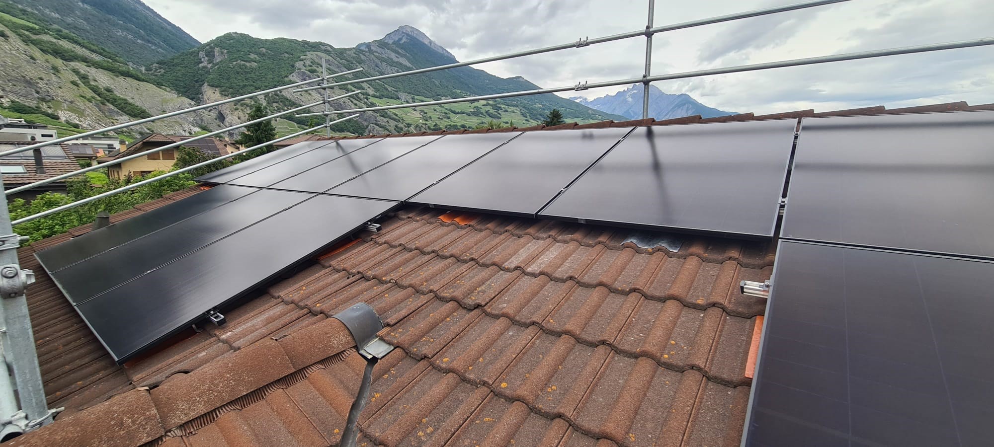 Maison familiale à toit en pente à Anières avec antennes TV, avant l'installation de panneaux solaires.