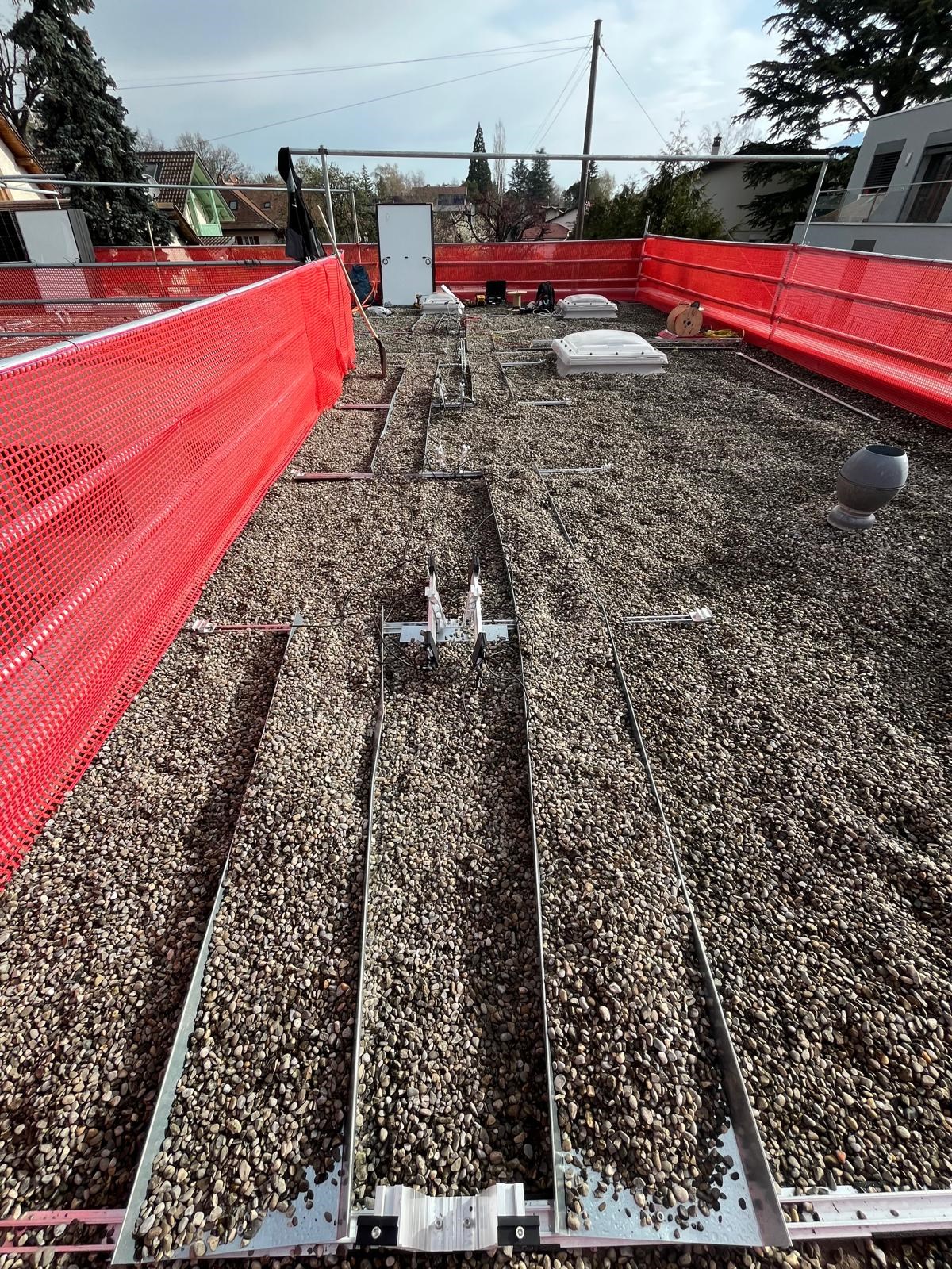 Pose de panneaux photovoltaïques sur toiture plate d’une maison en Suisse, dans le cadre d’une installation solaire résidentielle en zone urbaine.