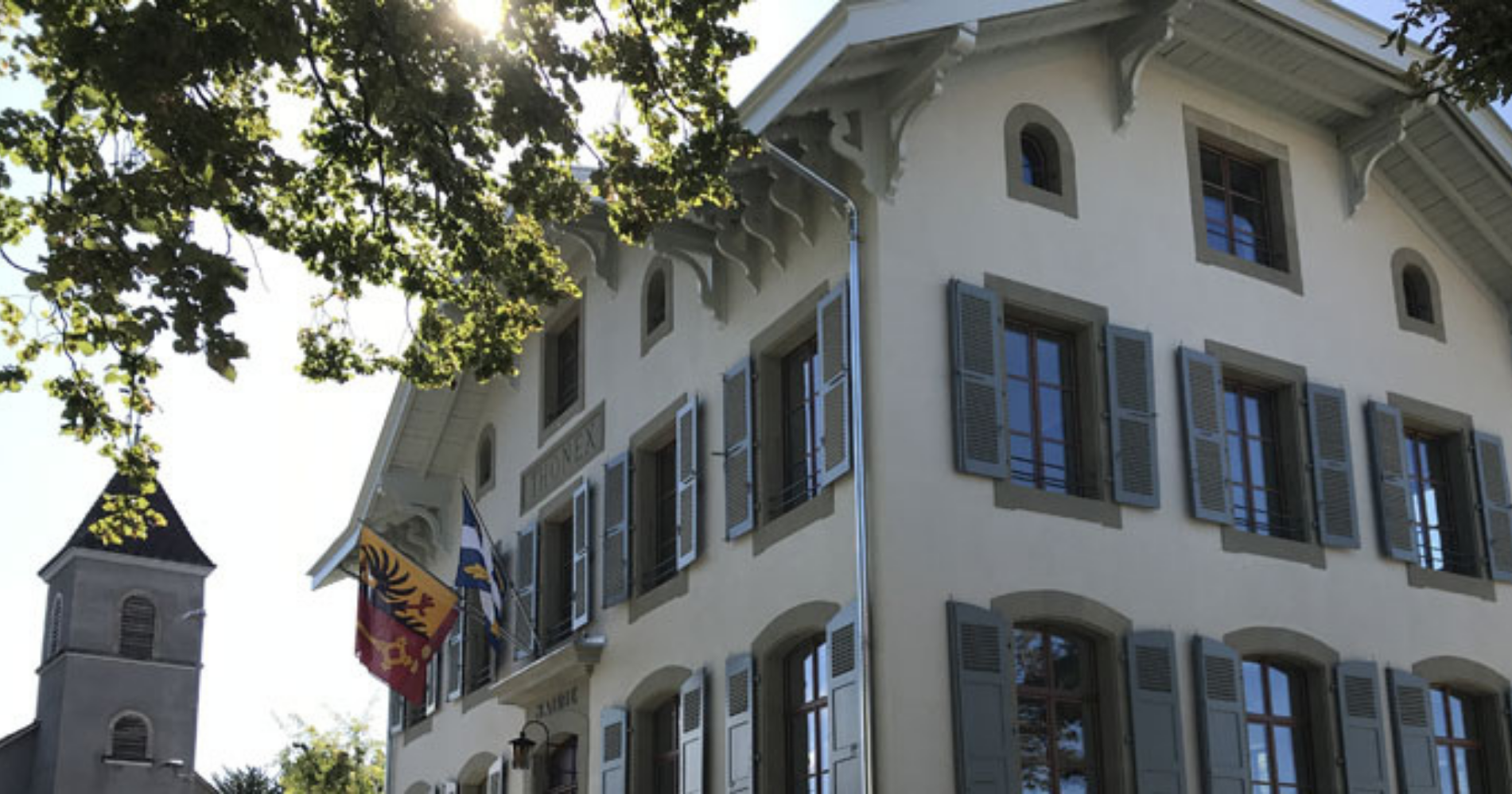 Mairie de Thônex ensoleillée avec le drapeau du canton de Genève et de la commune de Thônex.
