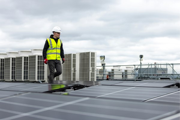 un homme marchant sur un toit disposant de panneaux solaires